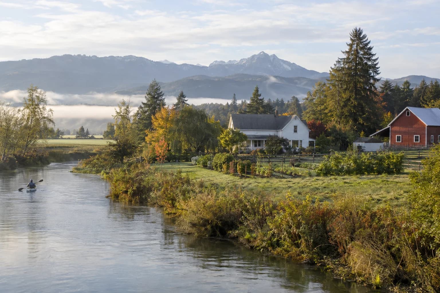 Restored farmhouse with a red barn and a kitchen garden in Carnation, Washington, with Snoqualmie Valley farmland with valley fog lifting and Cascade foothills