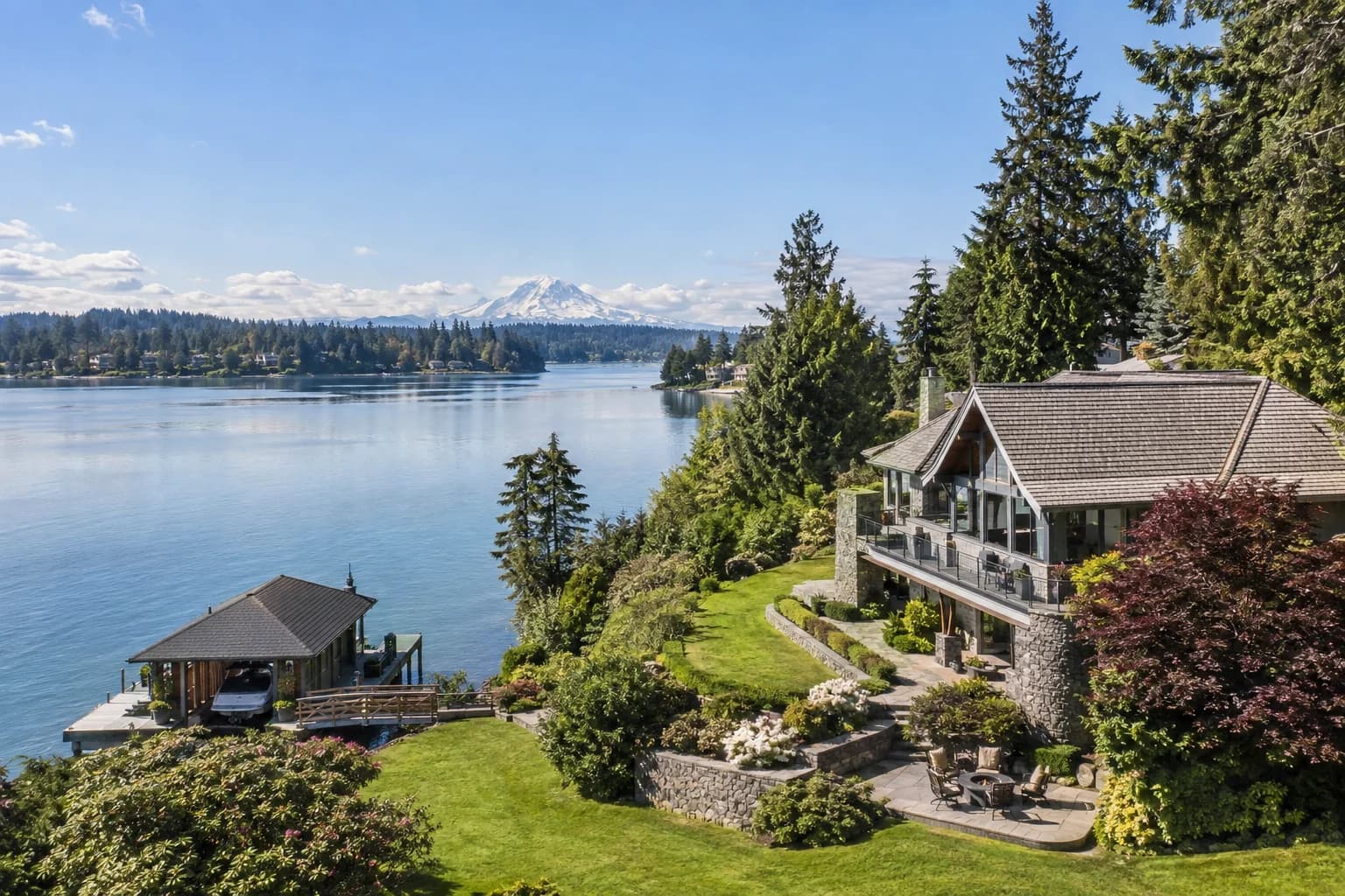 Lakefront estate home with a boathouse in Lakewood, Washington, with American Lake with a lawn running to the water and Mount Rainier across the lake