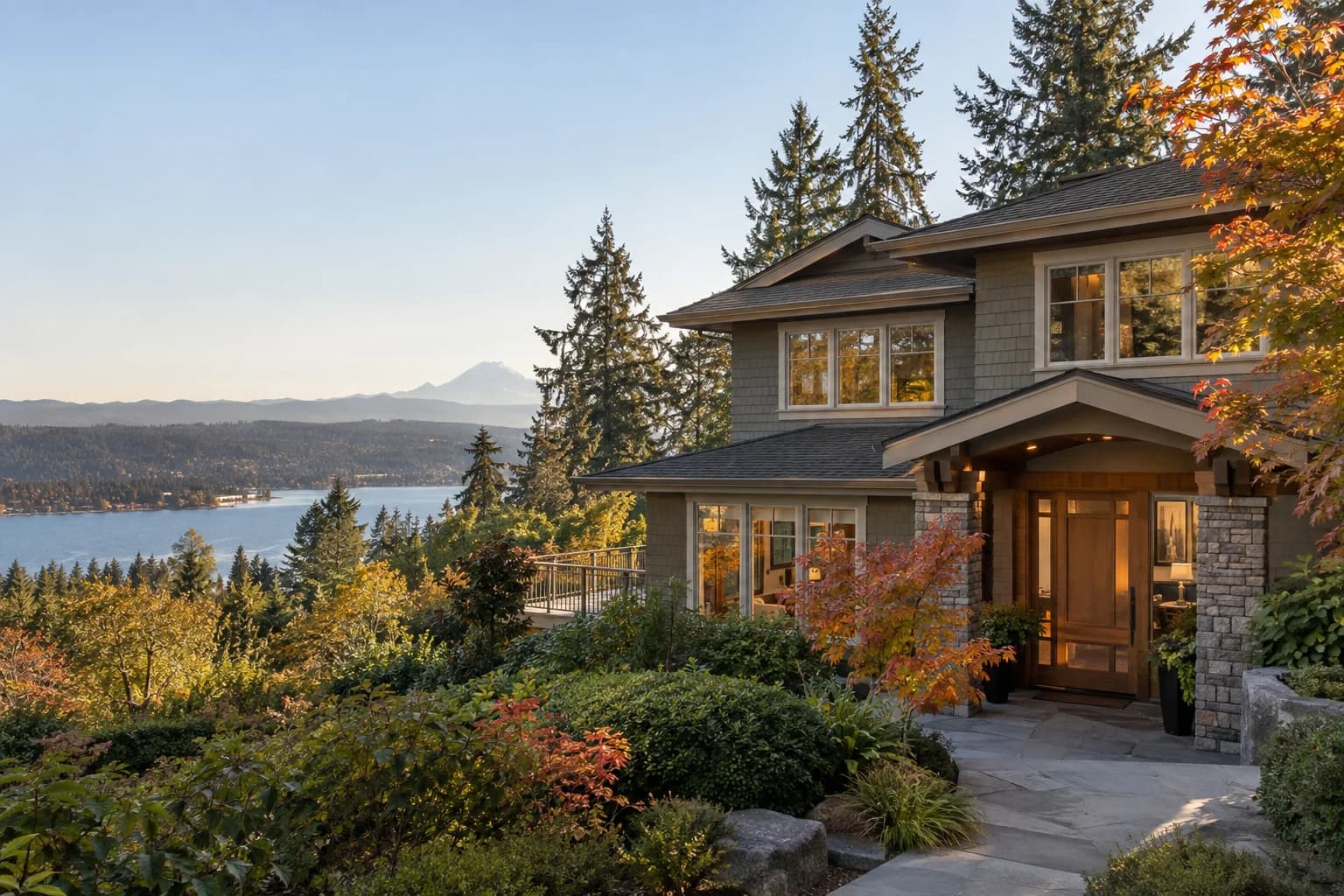 Two-story Northwest home with a big back deck under firs in Sammamish, Washington, with the Sammamish Plateau with Lake Sammamish glinting below and evergreens all around