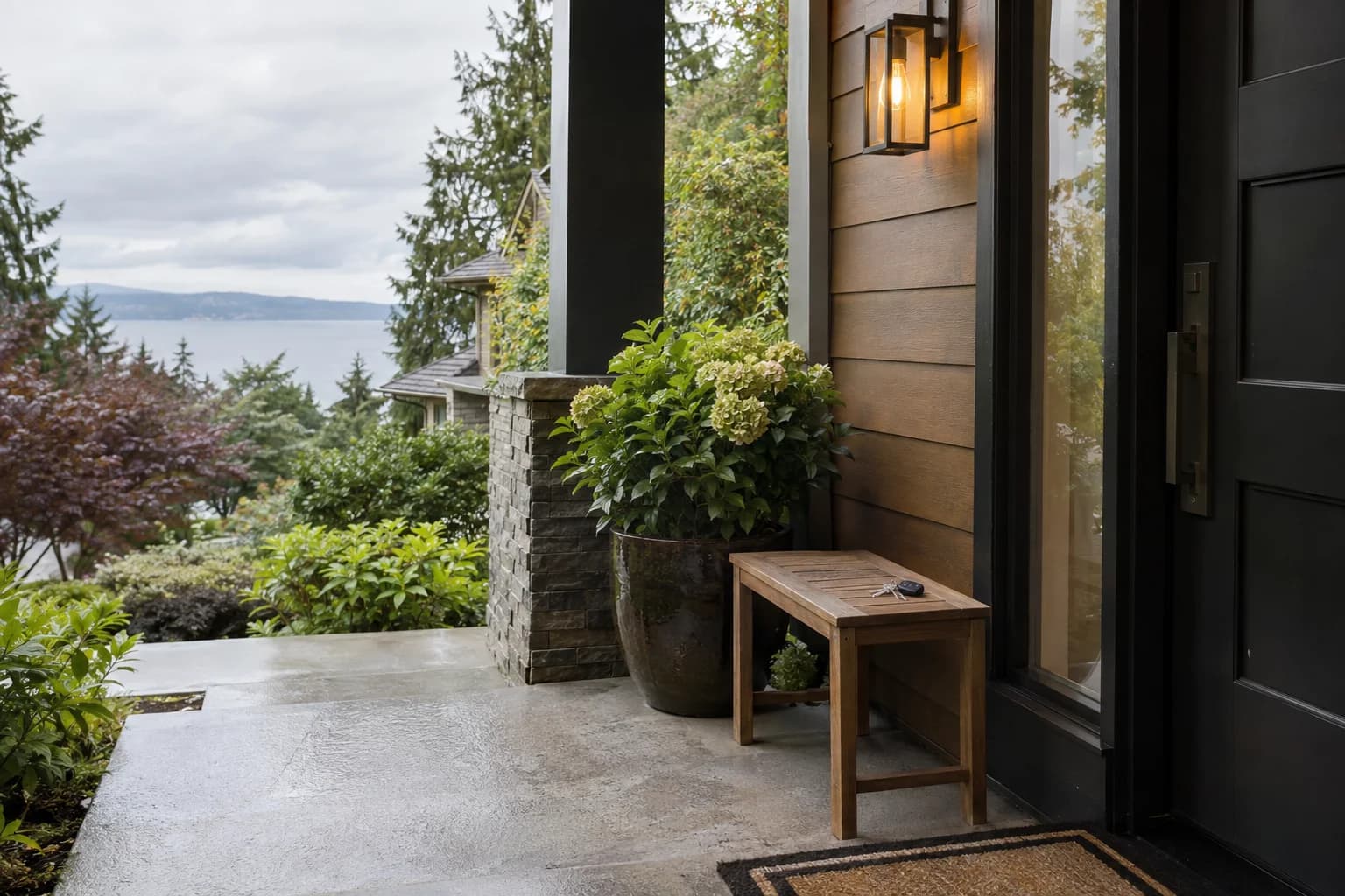 Rainy front porch of a well-kept rental townhome, keys on a small wood bench in Seattle — RexMont Real Estate