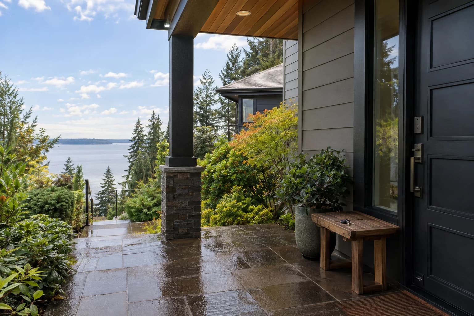 Rainy front porch of a well-kept rental townhome, keys on a small wood bench in Seattle — RexMont Real Estate
