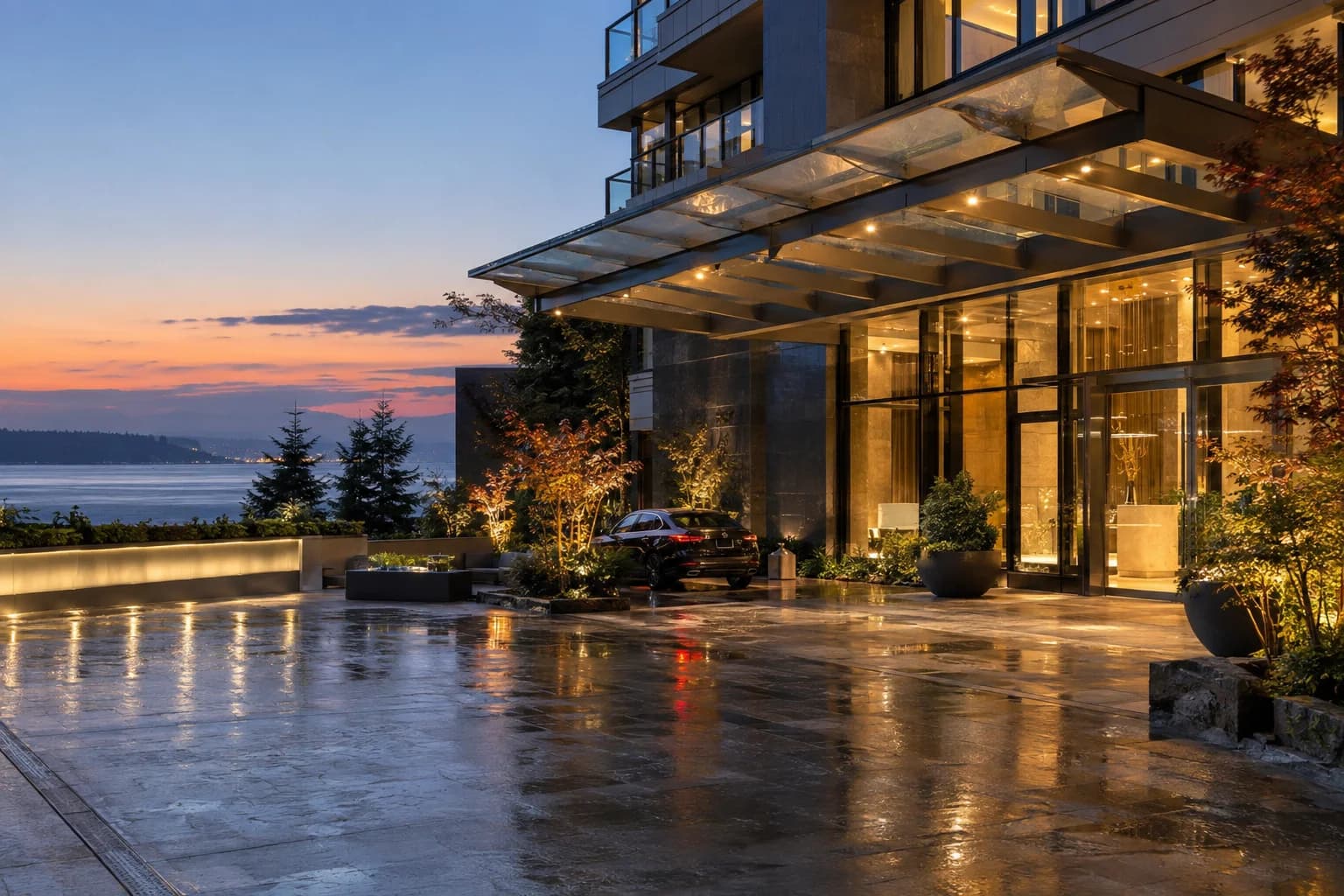 luxury high-rise lobby arrival, wet pavement, glass canopy, warm interior light in Seattle — RexMont Real Estate