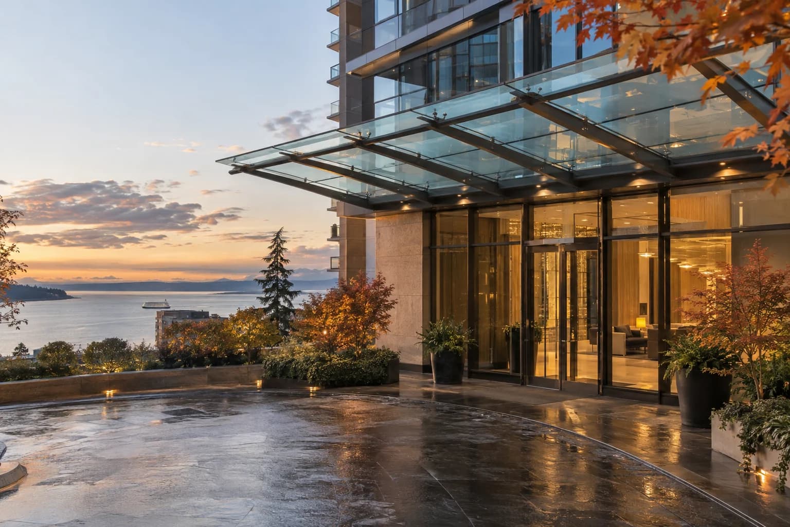 luxury high-rise lobby arrival, wet pavement, glass canopy, warm interior light in Seattle — RexMont Real Estate