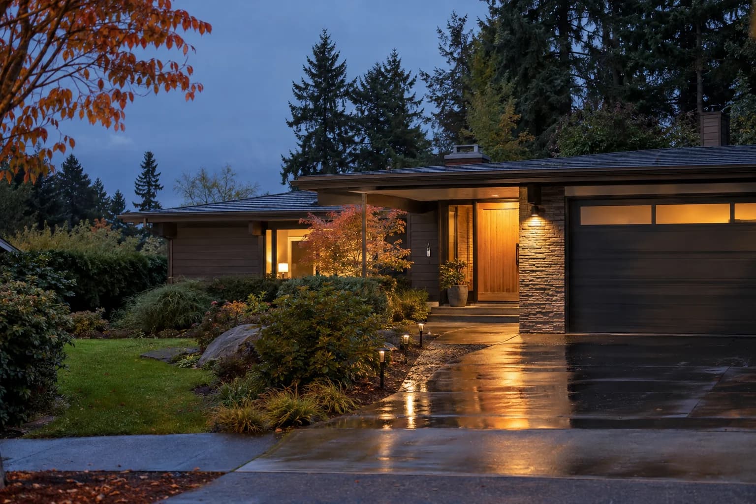 Mid-century Kirkland single-family house at dusk with a lit front door, wet driveway and a keyring on the porch hook — RexMont Real Estate